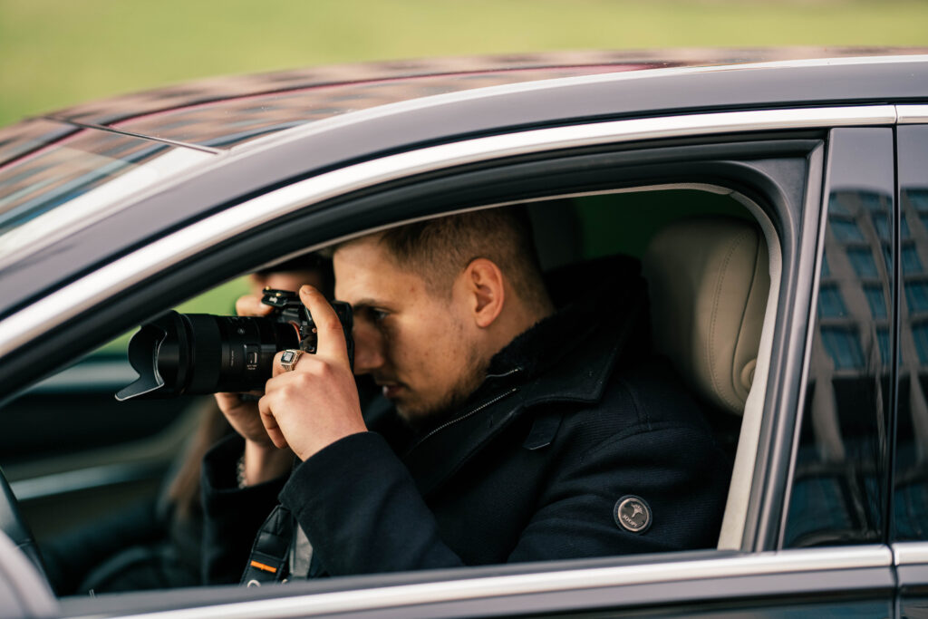 Ein Detektiv, der aus einem dunklen Auto heraus späht, mit einem Blick voller Entschlossenheit und Geheimnis.